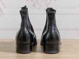 the back of a pair of black leather ankle boots on a wooden table