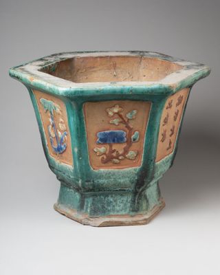 a green planter with flowers and birds on it