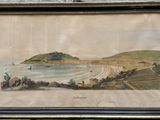 tableau représentant une vue de plage, encadré et accroché à un mur en pierre