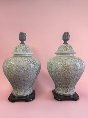 une paire de vases verts posés sur des socles en bois, sur fond rose