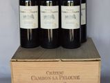 four bottles of red wine in a wooden box on a table