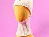 un bonnet blanc en tricot sur une tête de mannequin, sur fond rose