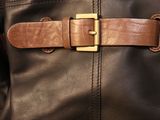 brown leather belt on a black leather jacket with a gold buckle