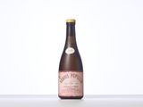 a bottle of wine sitting on top of a table next to a white wall