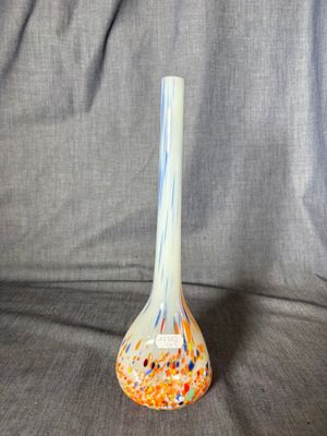 an orange and blue vase sitting on top of a gray cloth