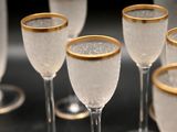 many wine glasses with gold rims sitting on a table