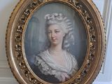 un portrait ancien représentant une femme en robe blanche, dans un cadre doré
