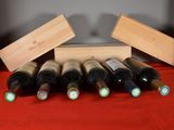 several bottles of wine sit in a wooden box on a red cloth
