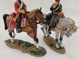 two figurines of men riding horses on a white surface