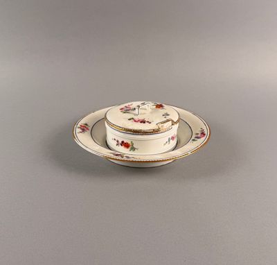 une assiette blanche ornée d'un motif floral, accompagnée d'une soucoupe