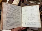 quelqu'un tient un livre sur lequel figure un dessin, devant une pile de livres