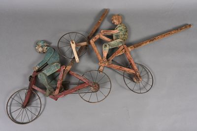 three wooden figurines of people riding on bicycles