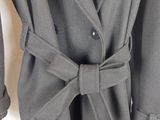 Le manteau est gris et comporte un grand nœud sur le devant