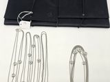an assortment of silver necklaces and bracelets on a white surface