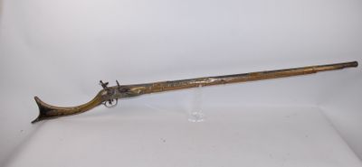 un vieux pistolet avec une poignée en bois sur une surface blanche