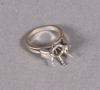 silver ring with a horse and rider on it on a gray surface