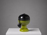 un vase noir et vert posé sur un socle blanc