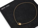 a black box with a gold necklace and a gold disc on it