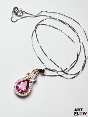 collier avec une pierre rose et une chaîne en argent sur fond blanc