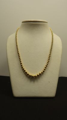 un collier en or sur un mannequin sur fond blanc