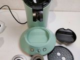 a green coffee maker sitting on top of a white counter