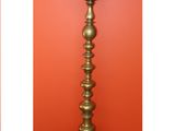 two different views of a tall brass candle stand against a red wall