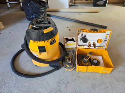 un aspirateur jaune et noir posé par terre à côté d'une boîte à outils