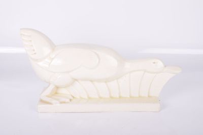 une image représentant une sculpture blanche d'un oiseau posé sur un socle en bois