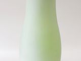 a small green vase sitting on a white surface