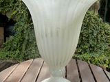 a glass vase sitting on a wooden table on a patio