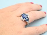 an image of a woman ' s hand holding a blue sapphire and diamond ring