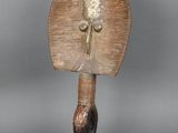 statue représentant un oiseau tenant une feuille, posée sur un socle en bois