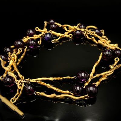 un gros plan d'un bracelet en or orné de perles violettes sur un fond noir
