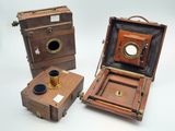 trois appareils photo anciens sont posés les uns à côté des autres sur une surface blanche