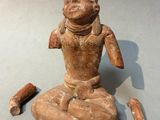 une image représentant une statue d'une personne assise par terre à côté d'un marteau