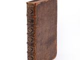 an old book with a brown cover sitting on top of a white surface