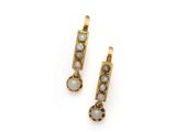 une photo d'une paire de boucles d'oreilles en or ornées de pierres blanches
