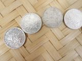 four different types of silver coins sitting on top of a wooden table