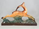 figurine of a running deer on a green and brown base