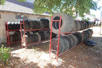 many tires stacked on a rack in front of a house