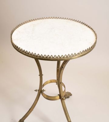 une table avec un plateau en marbre blanc et un piètement en métal doré