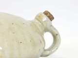 a white jug with a brown handle sitting on a white surface