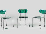 trois chaises vertes placées les unes à côté des autres sur une surface blanche