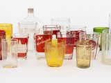 de nombreux vases en verre de différentes couleurs posés sur une surface blanche