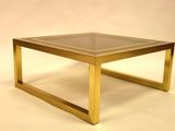 a glass top coffee table with a gold frame