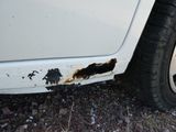 une voiture blanche avec de la rouille sur le côté