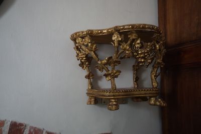 une horloge accrochée au mur, à côté d'une étagère dorée