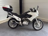 a white motorcycle parked in a garage with a black seat