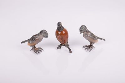 three small birds sitting on top of each other on a white surface
