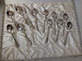 six silver spoons in a box on a white cloth
